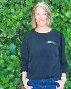 Kate - Operations Manager at Seamless Bookkeeping (a bookkeeping firm based in Geelong Victoria servicing clients Australia wide) wearing a black t-shirt with 'Seamless Bookkeeping' text against a green leafy background